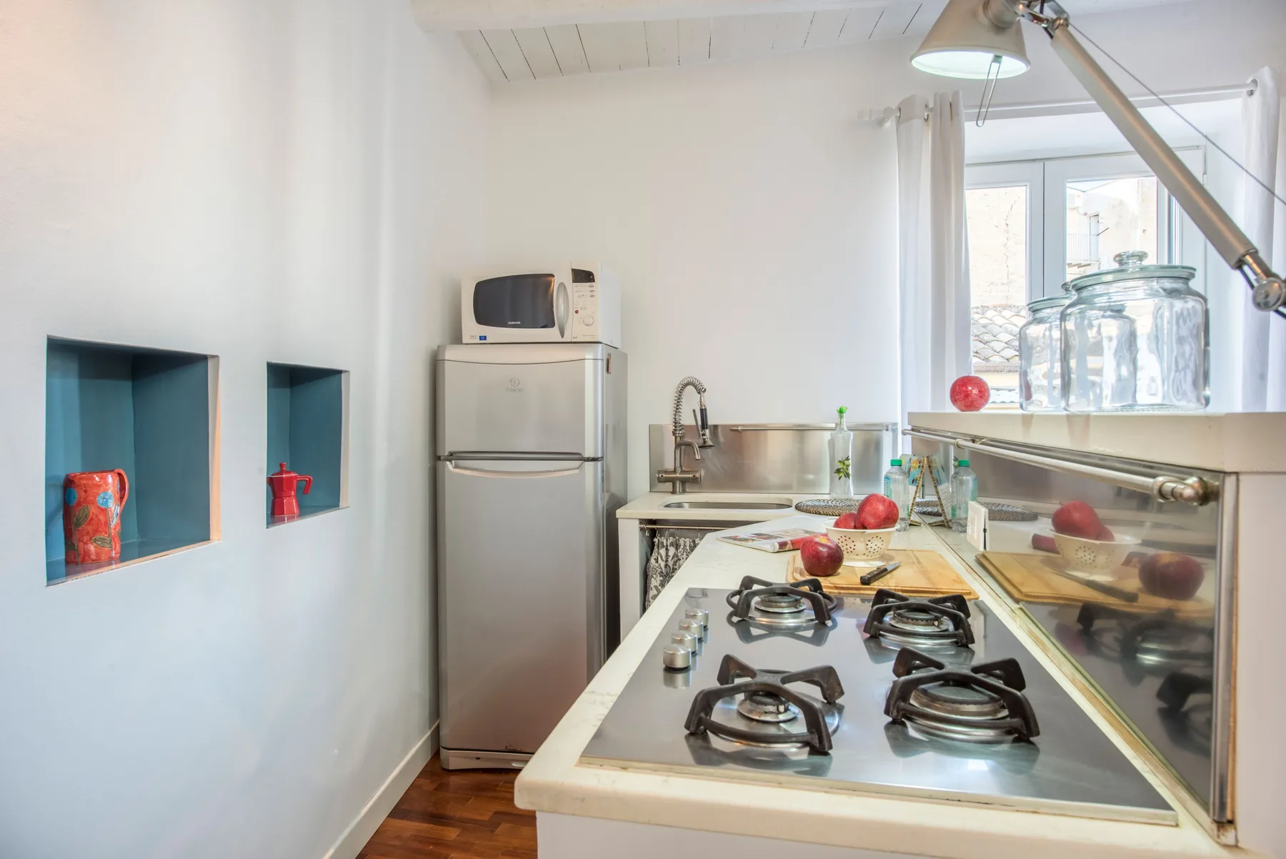 A compact kitchen with a stainless-steel refrigerator and a gas cooktop.