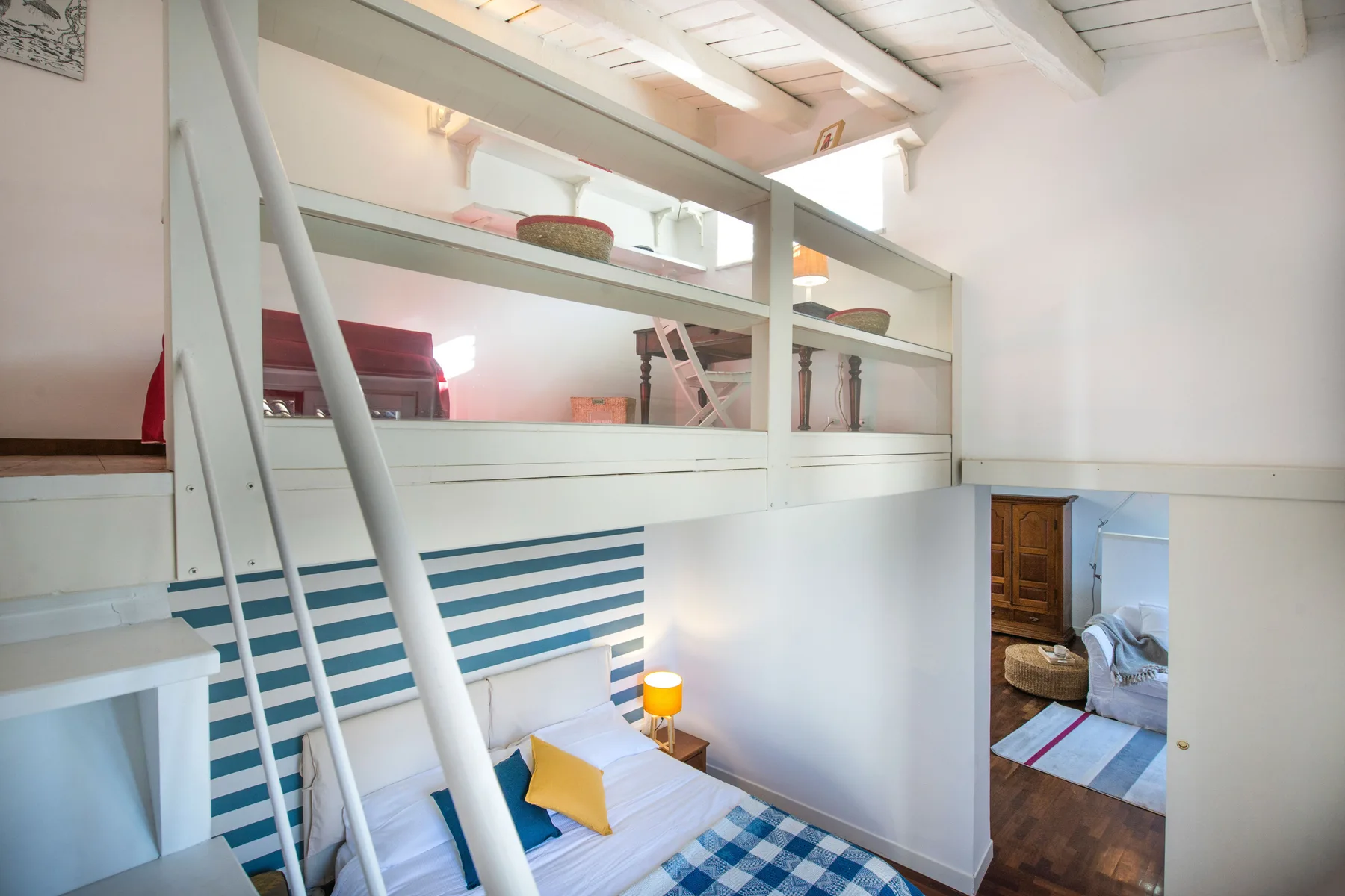 A bright loft bedroom with a raised sleeping area and a ladder.