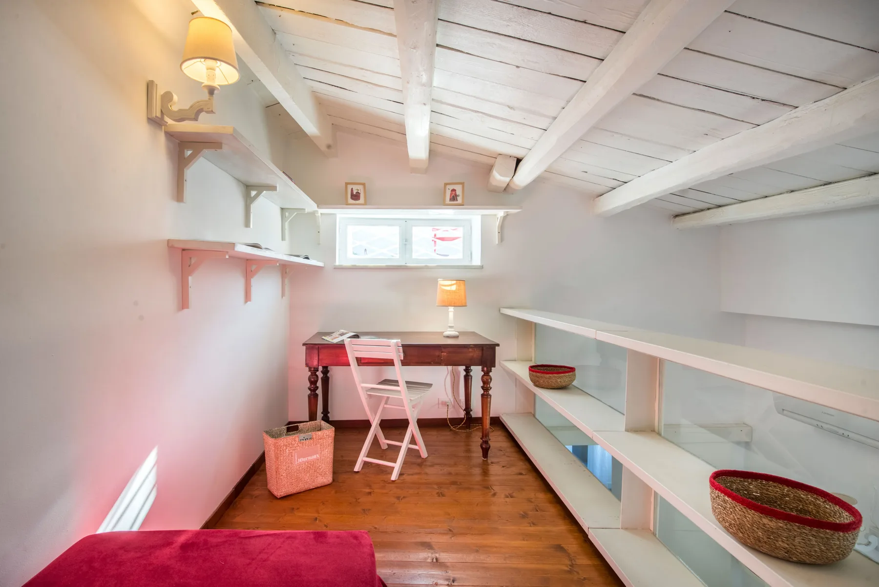 A small attic workspace with a desk, chair, and built-in shelves.