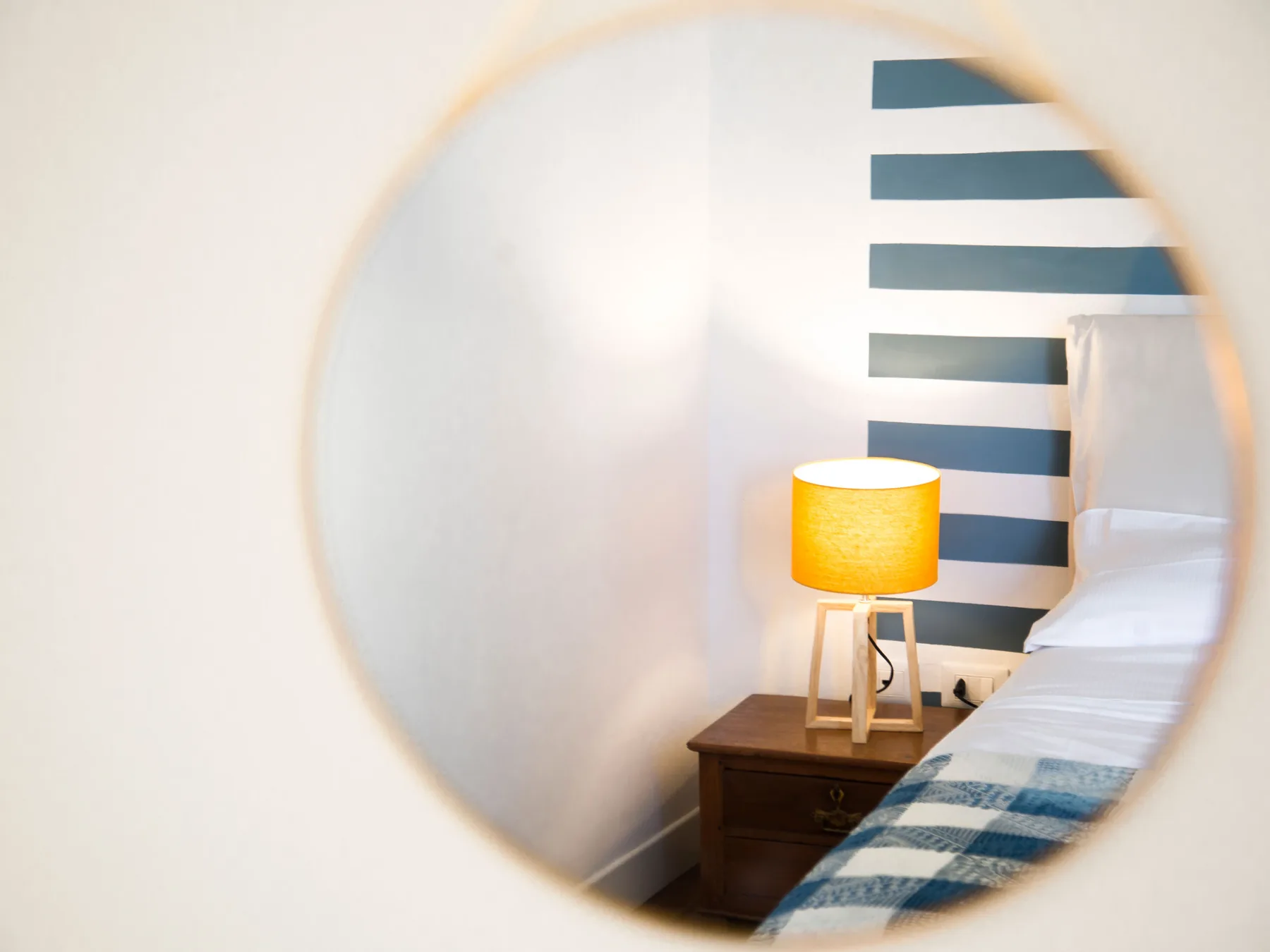 A bedroom with a bedside table and a warm-lit lamp beside the bed.