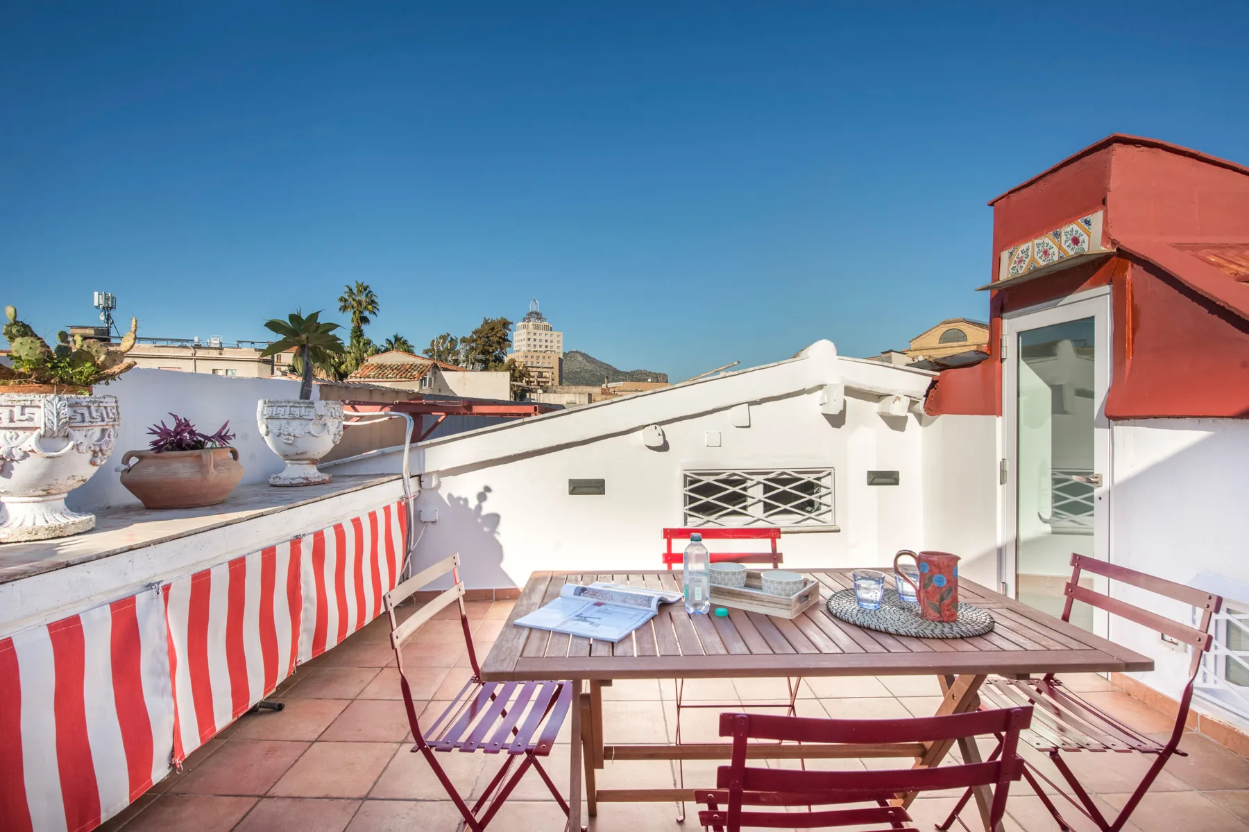 A rooftop terrace with a patio table and seating under a clear blue sky.