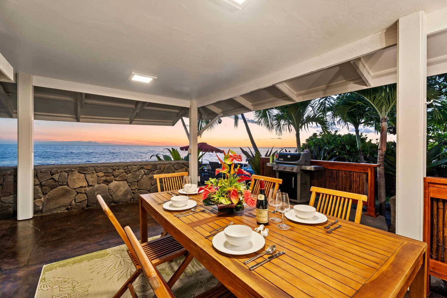 Comedor cubierto junto al mar, con una mesa de madera preparada para comer.