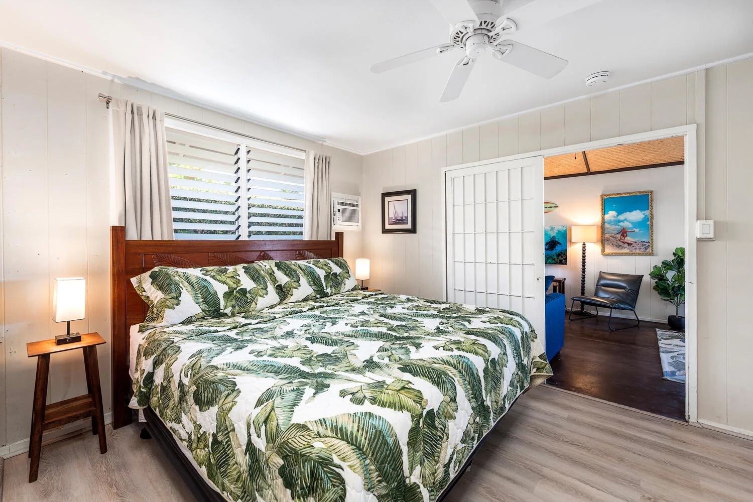 Un dormitorio con una cama grande, ropa de cama estampada y una ventana con cortinas.