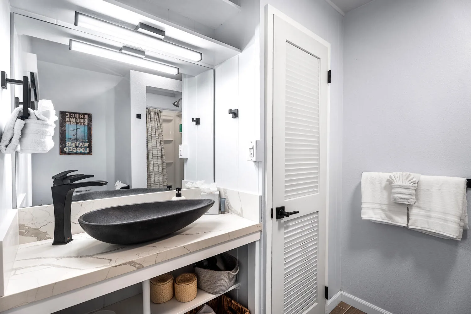 Un tocador de baño con lavabo sobre encimera y un espejo grande.