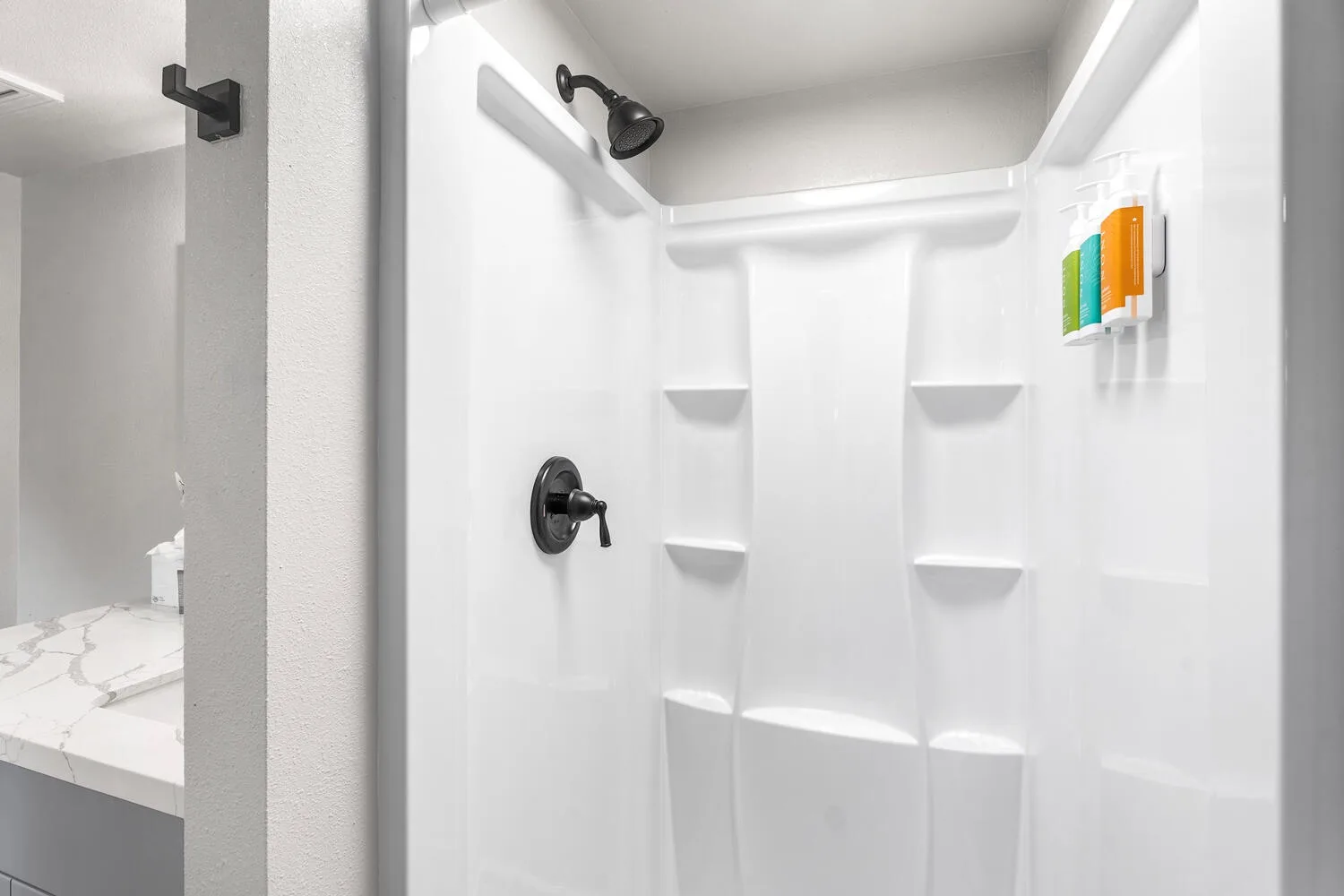 Una zona de ducha luminosa con estantes empotrados y un cabezal de ducha en la pared.