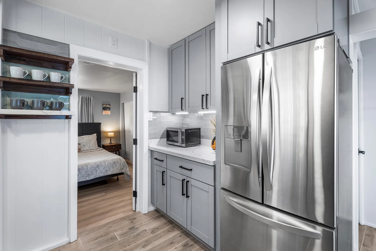 Una cocina compacta con gabinetes grises, un microondas y un refrigerador de acero inoxidable.