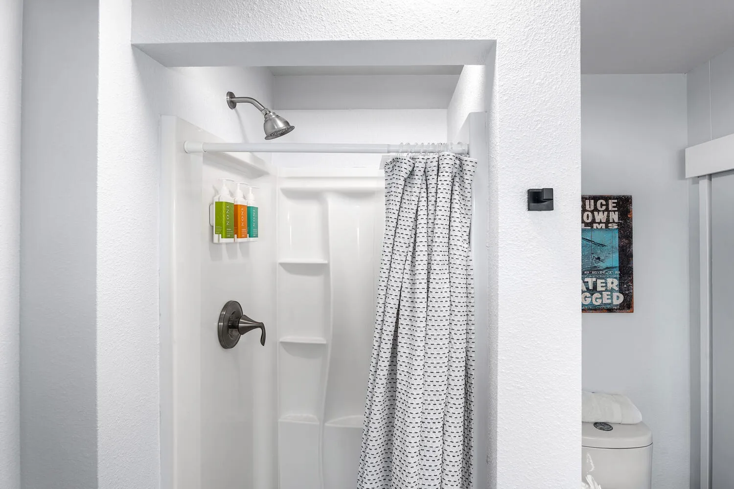 Un baño con una ducha y una cortina estampada.