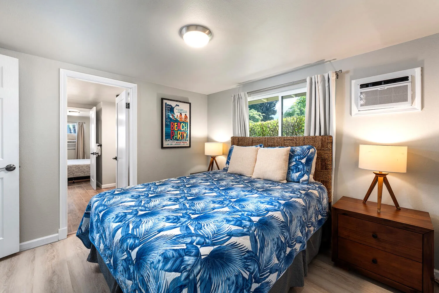 Un dormitorio con una cama cubierta de ropa de cama floral azul junto a una ventana.