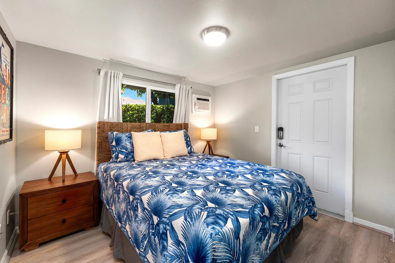 Un dormitorio con una cama cubierta con ropa de cama estampada en azul y blanco y una ventana detrás.