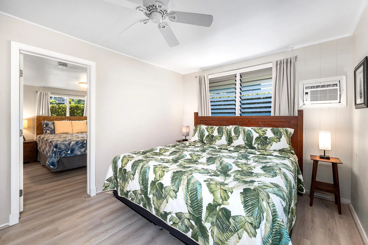 Un dormitorio con una cama cubierta de ropa de cama con hojas verdes y una ventana detrás.