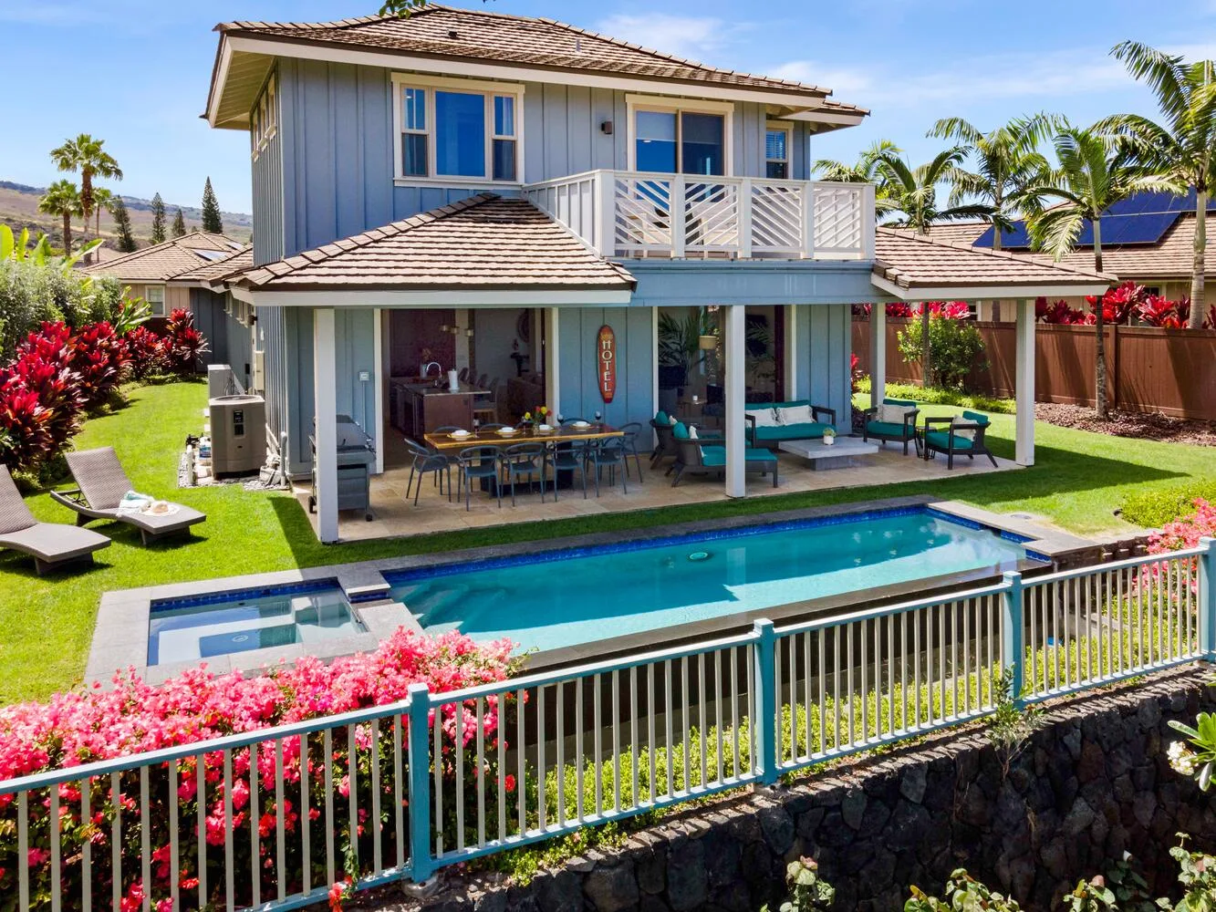 A two-story house overlooks a swimming pool and patio seating.