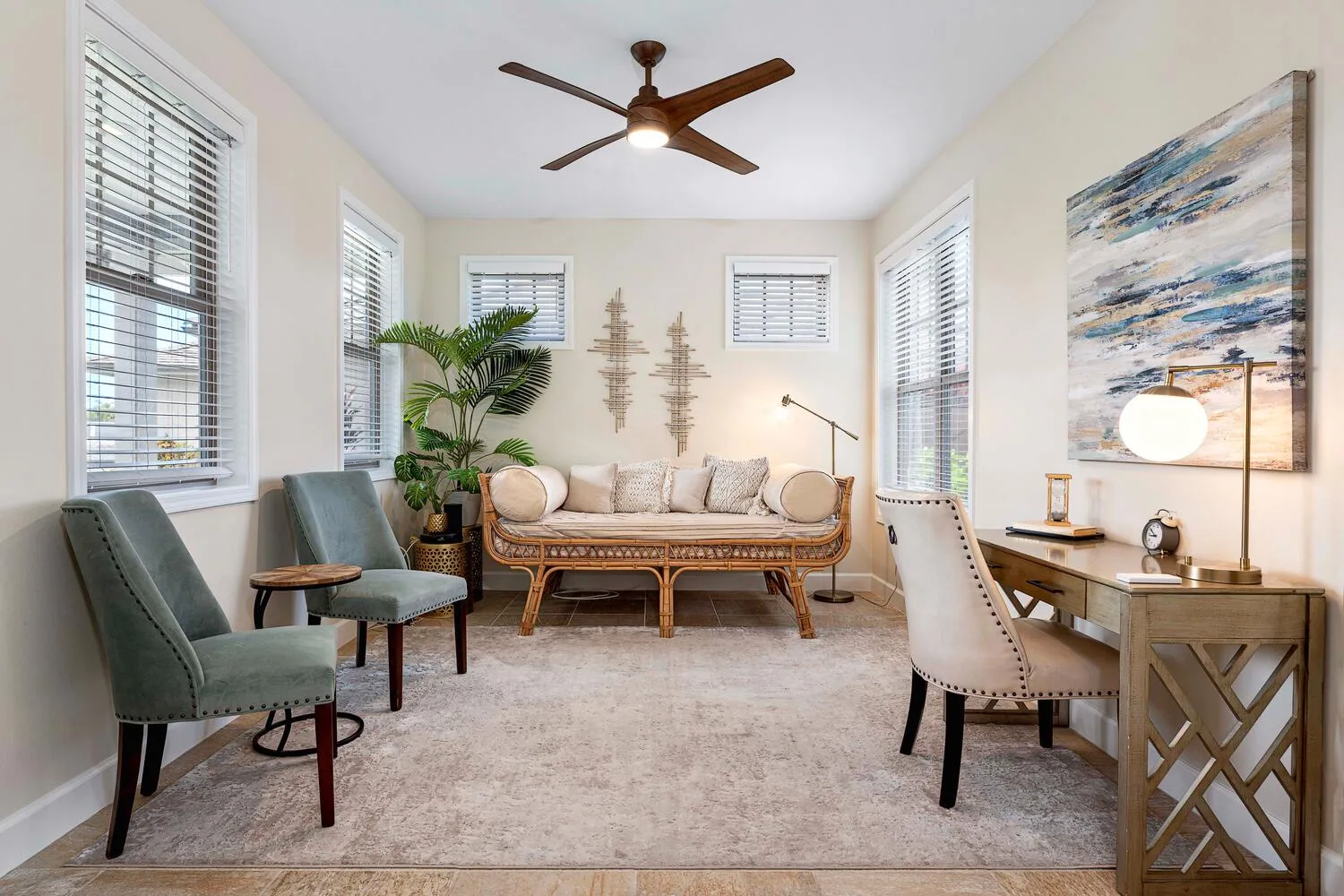 A bright sitting room with seating, large windows, and a desk.