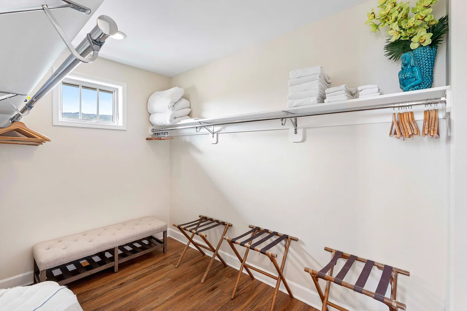 A walk-in closet with open shelving, hanging space, and folding luggage racks.