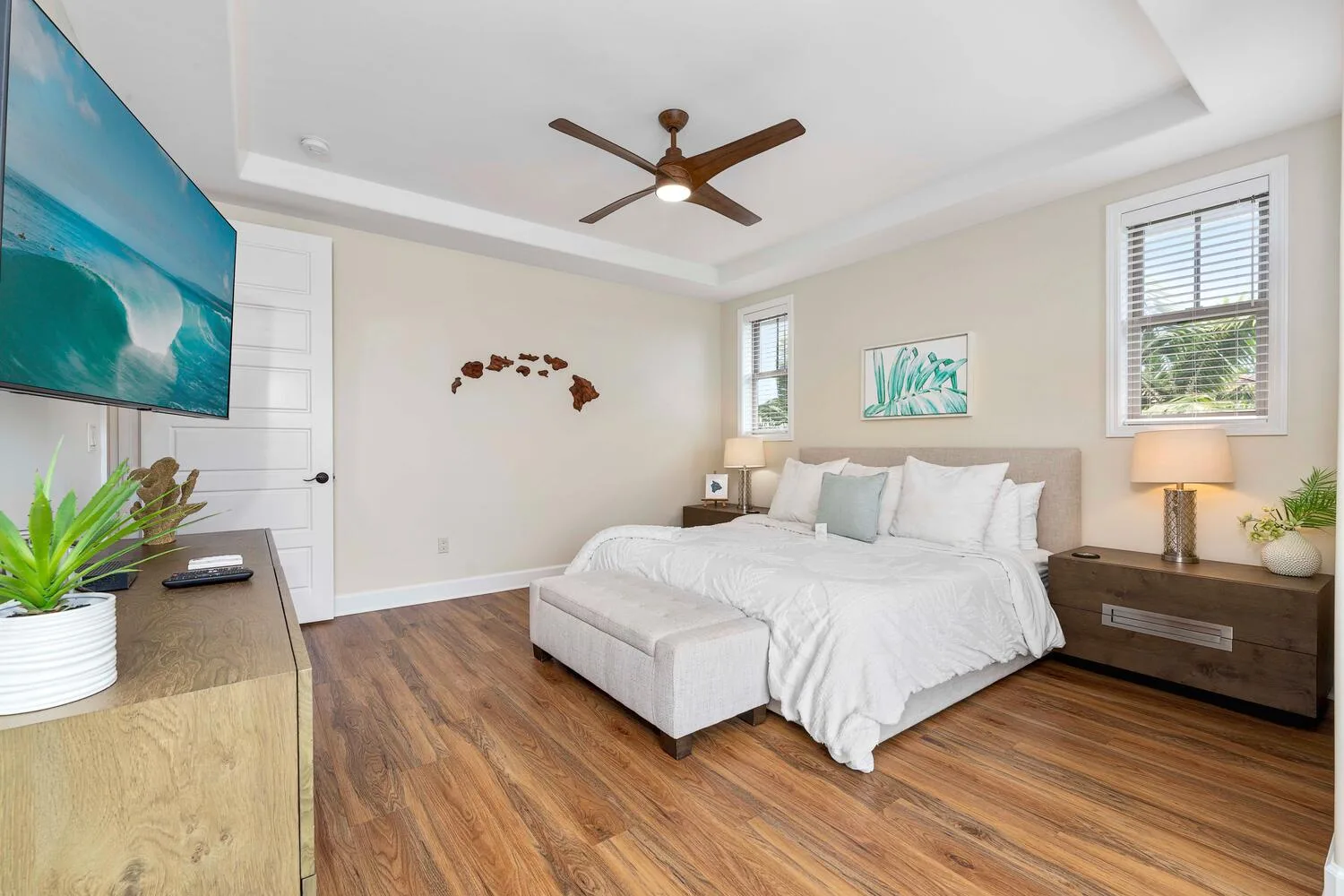 A bright bedroom with a large bed, bedside tables, and windows.