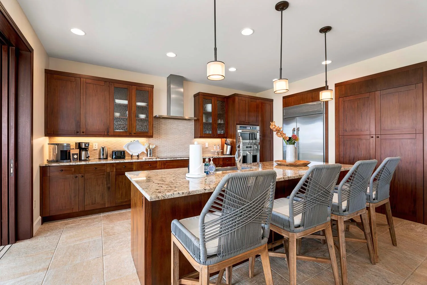 A spacious kitchen with a central island, wooden cabinets, and bar seating.