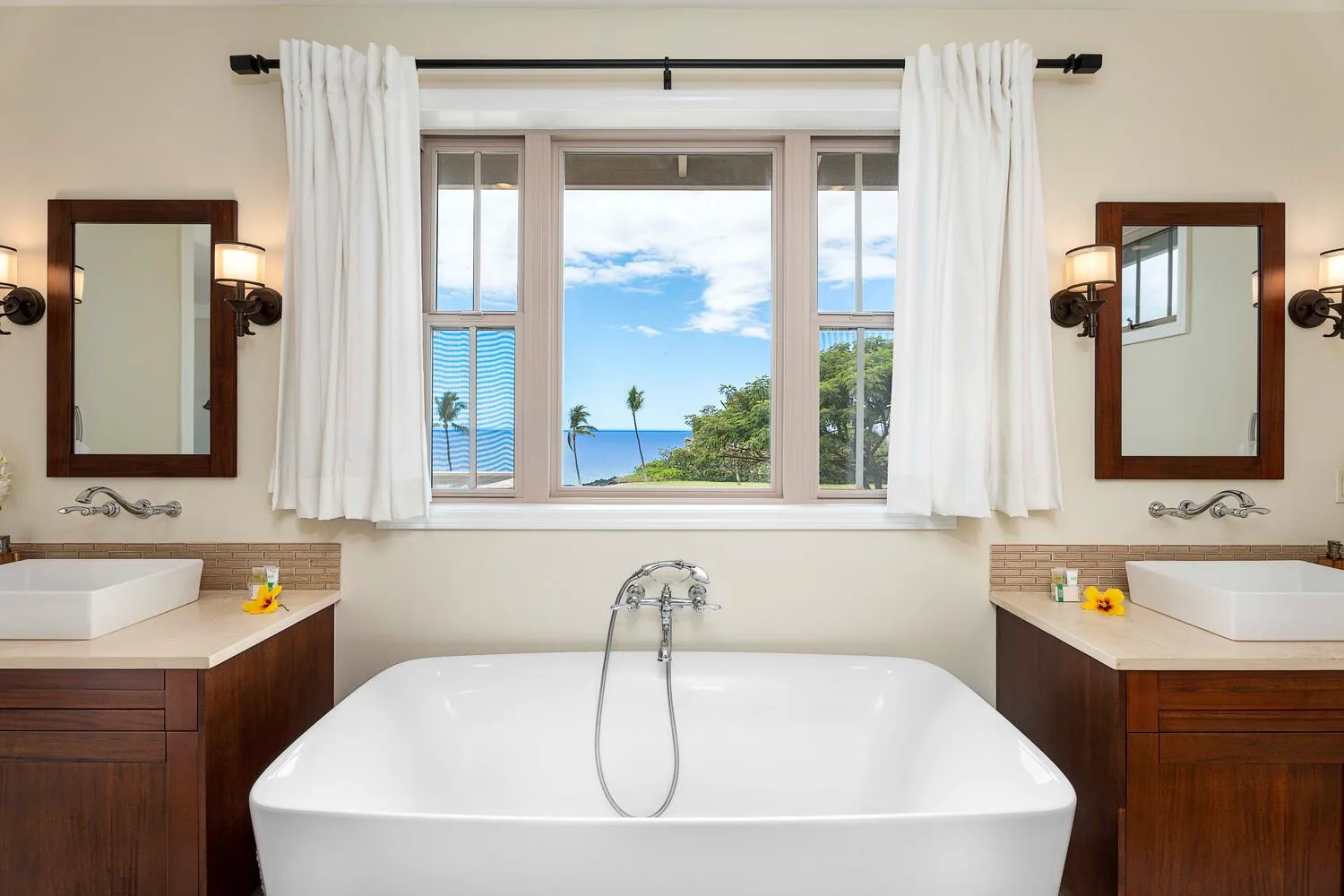 A bathroom with a bathtub beneath a large window overlooking the sea.