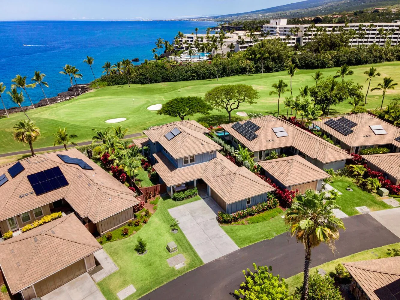 Aerial view of homes beside a green golf course and the ocean.