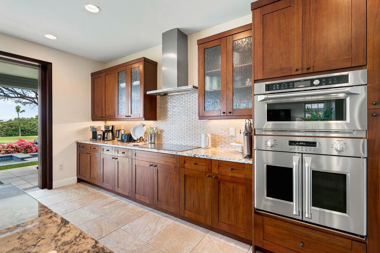 A kitchen with wooden cabinets, tiled backsplash, and stainless-steel appliances.
