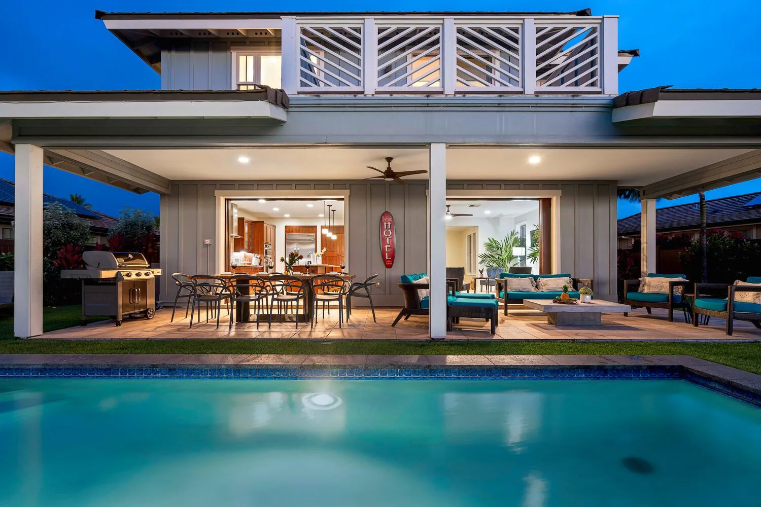 A modern house opens onto a covered patio beside a swimming pool.