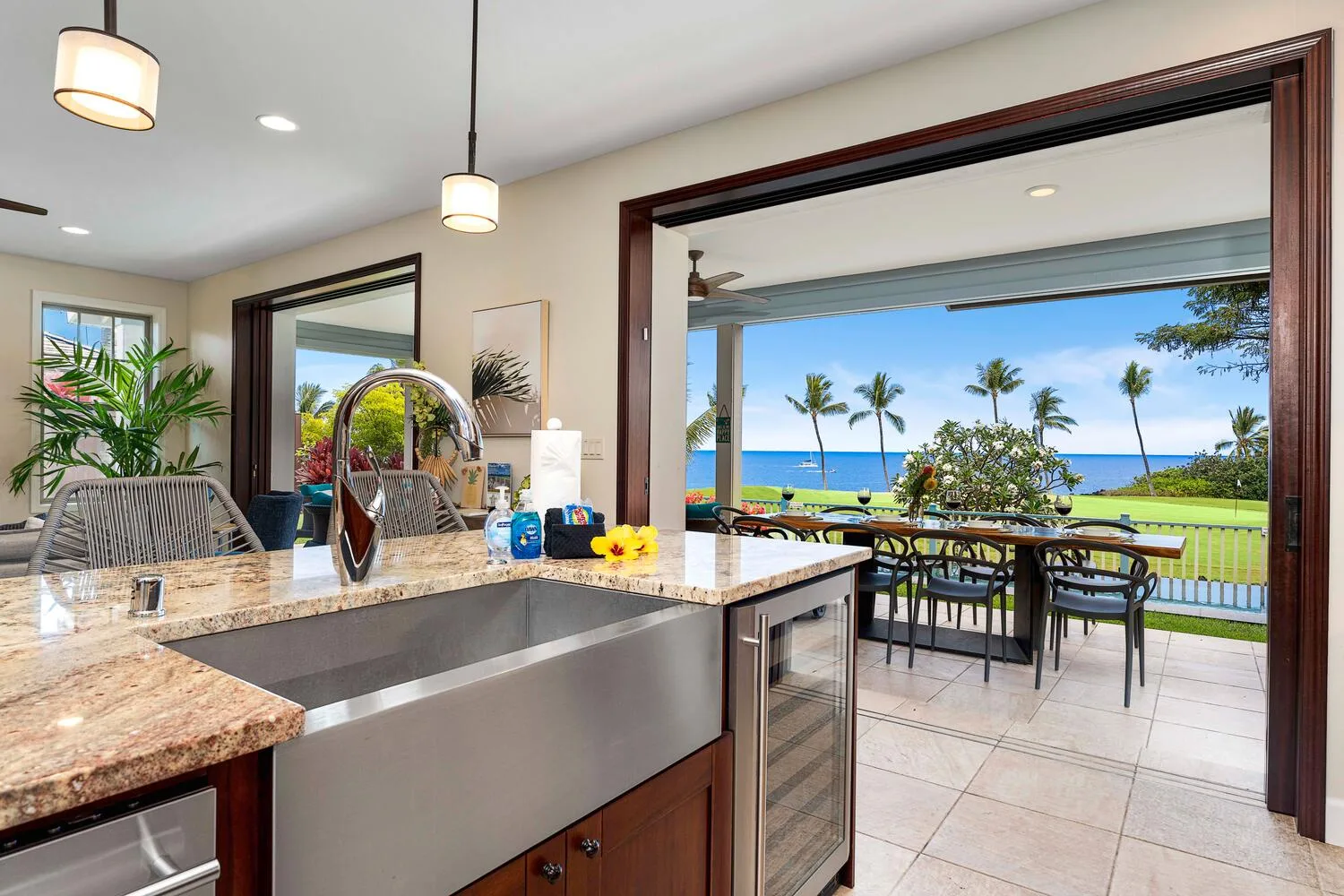A kitchen opens onto an outdoor dining area overlooking the ocean.