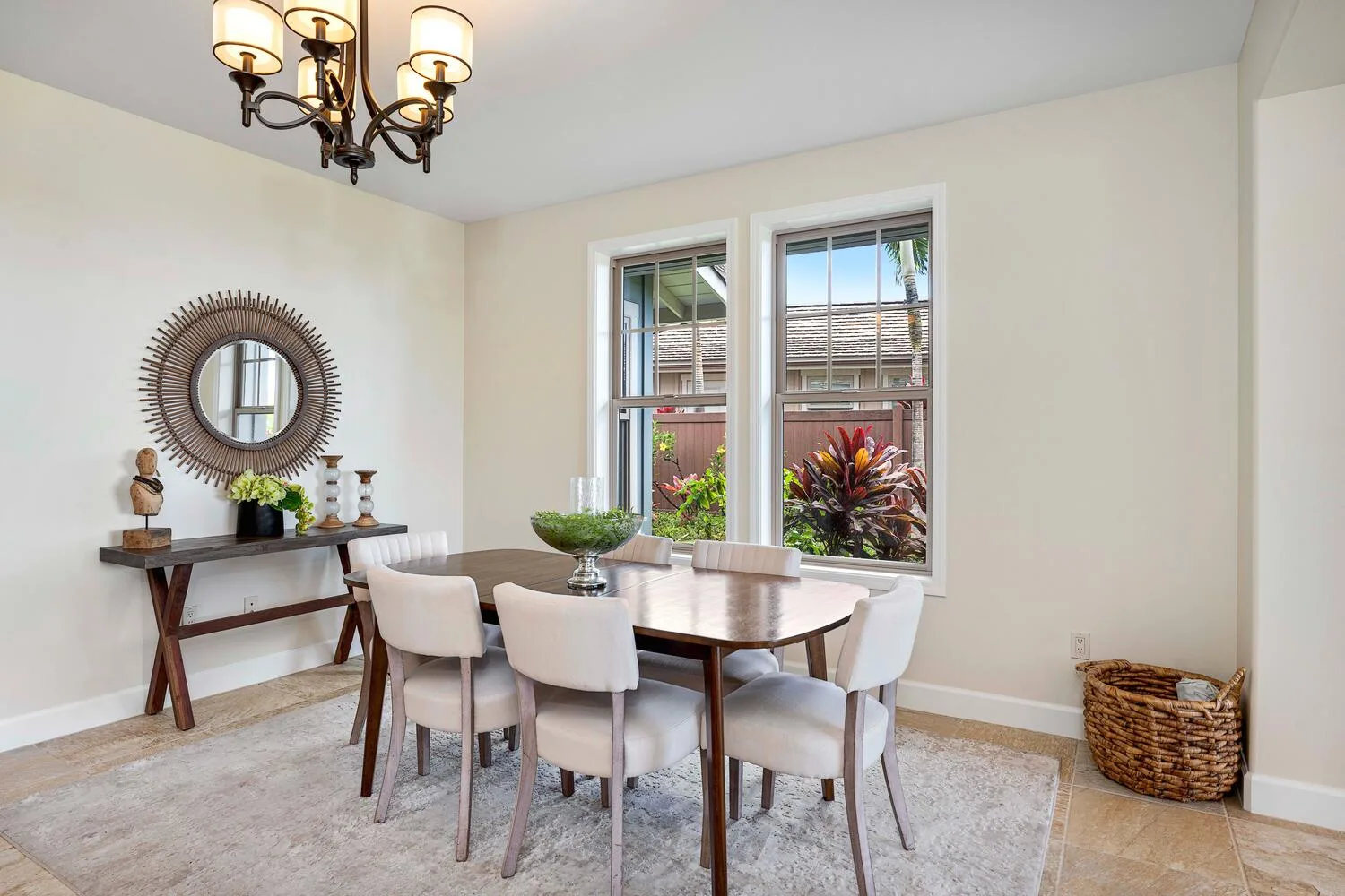 A bright dining area with a wooden table, chairs, and two windows.