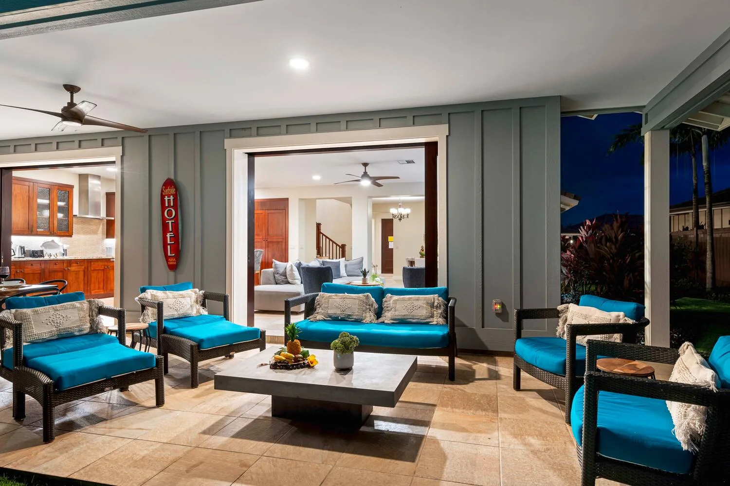 A covered patio lounge with turquoise seating and a view into the living room.