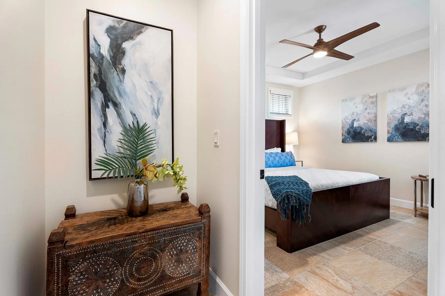A bedroom with a dark bed, blue bedding, and matching wall art.
