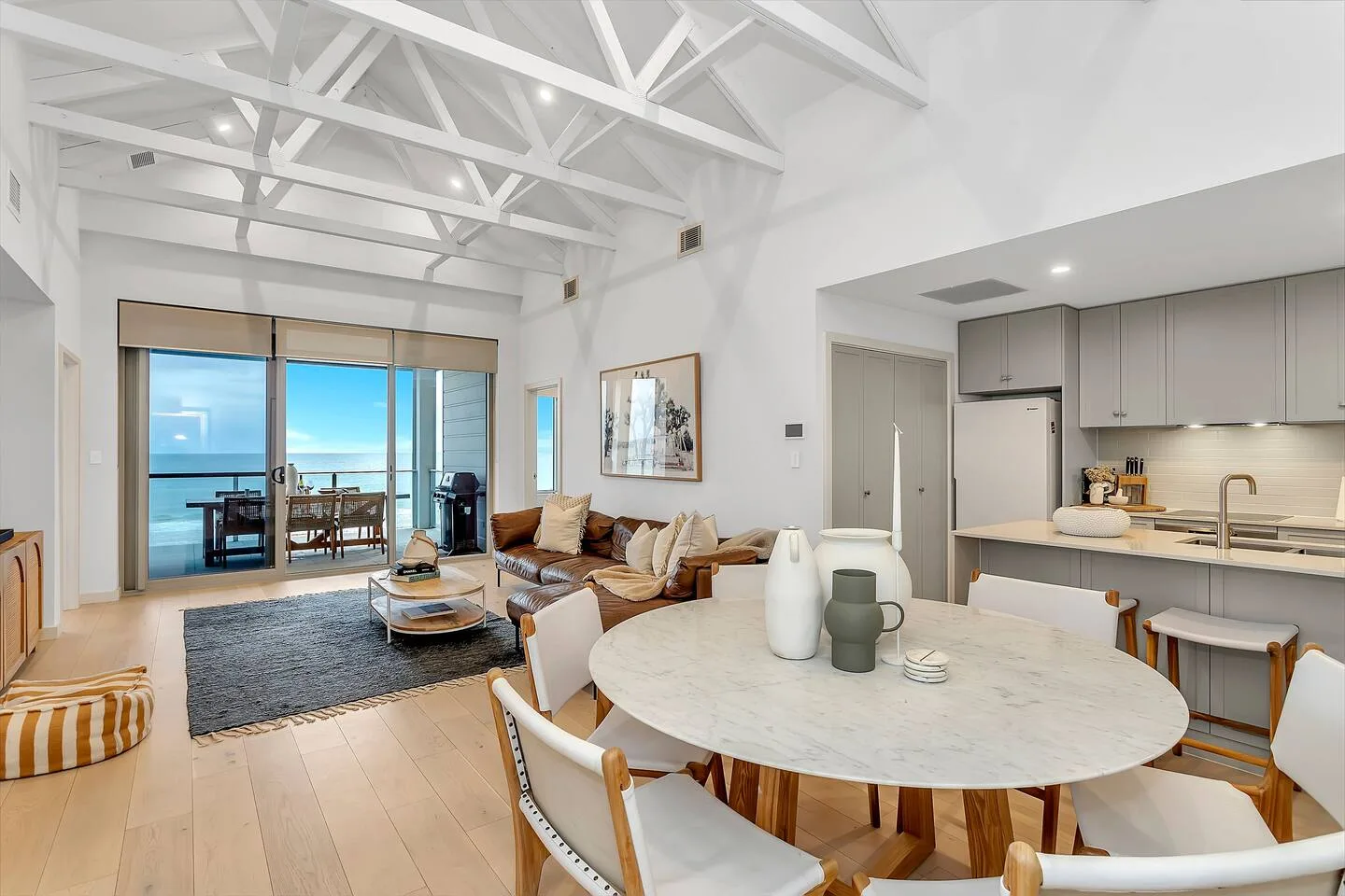 Una sala-comedor de planta abierta con cocina y grandes ventanales.