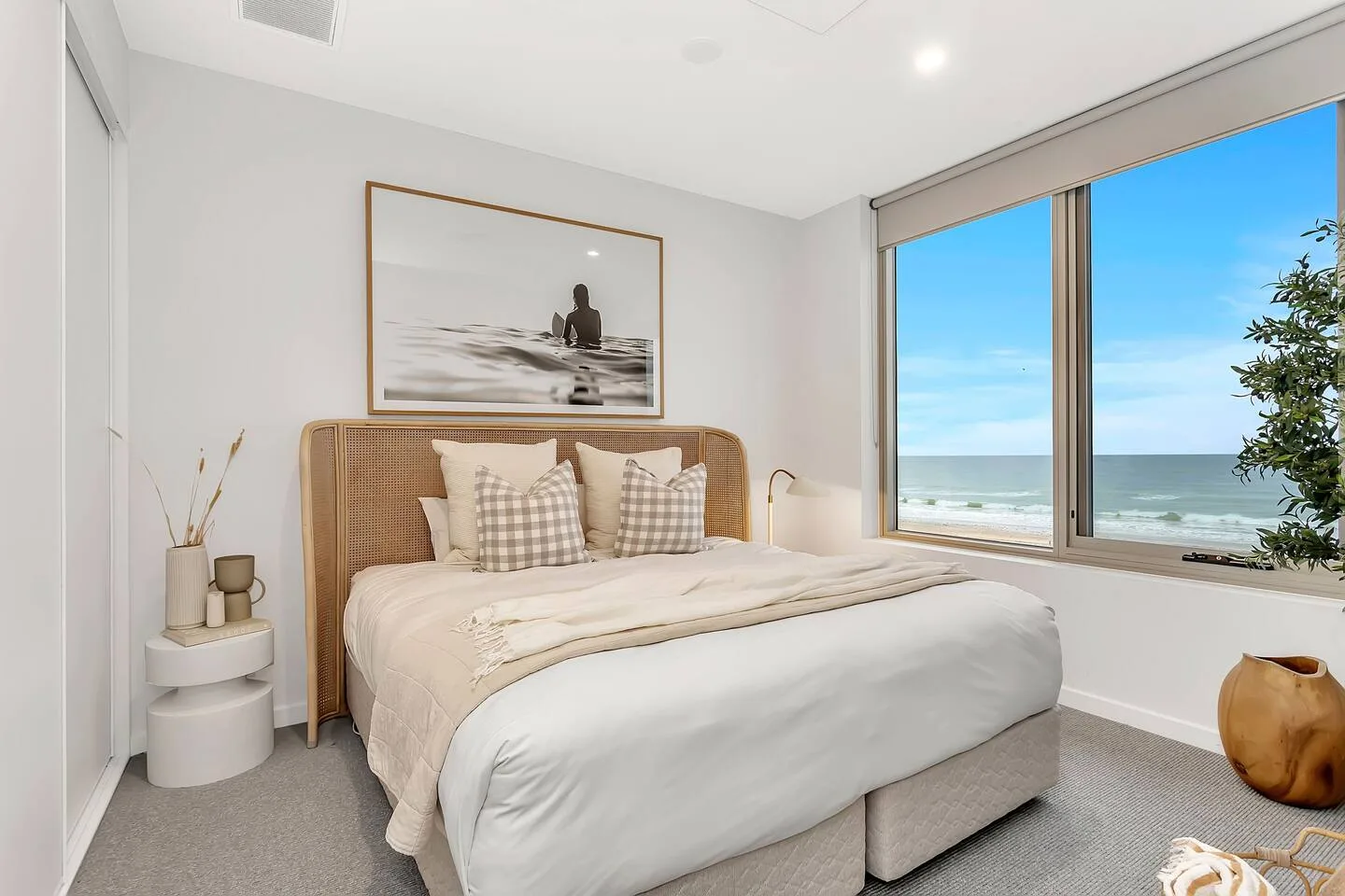 Un dormitorio luminoso con una cama junto a una gran ventana con vistas al océano.