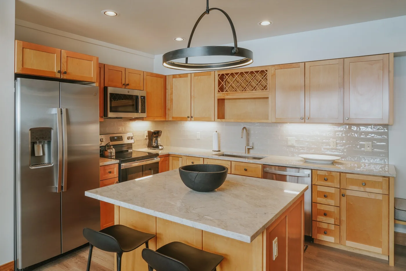 Una cocina con gabinetes de madera, electrodomésticos de acero inoxidable y una isla grande.