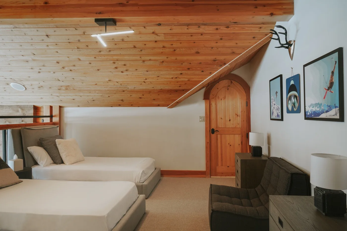 Un dormitorio con dos camas, un techo de madera inclinado y una zona de estar.