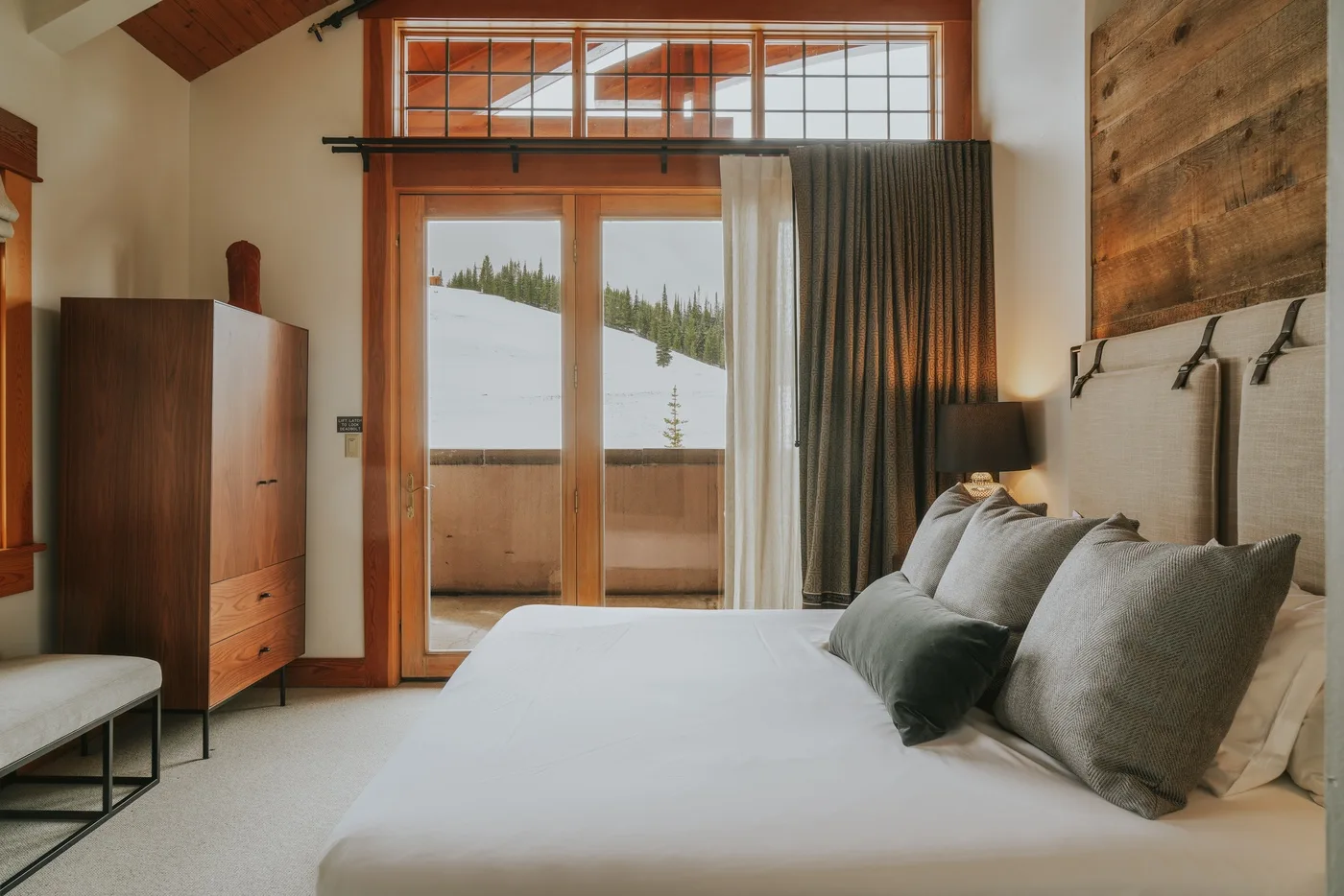 Un dormitorio con una cama y grandes ventanas con vistas a un paisaje nevado.