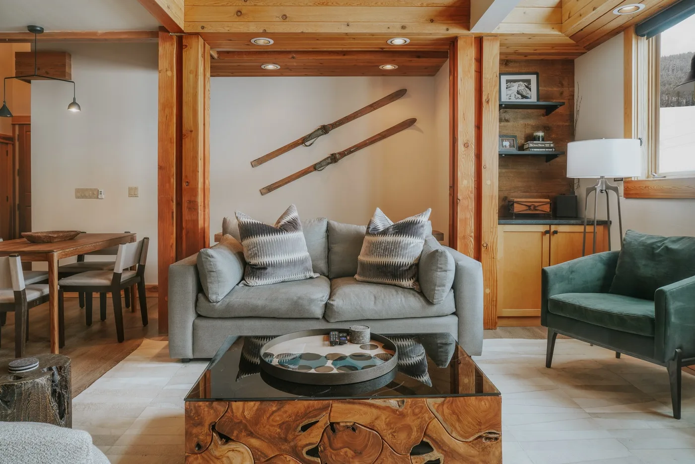 A living room with a gray sofa, a glass coffee table, and wooden ceiling beams.