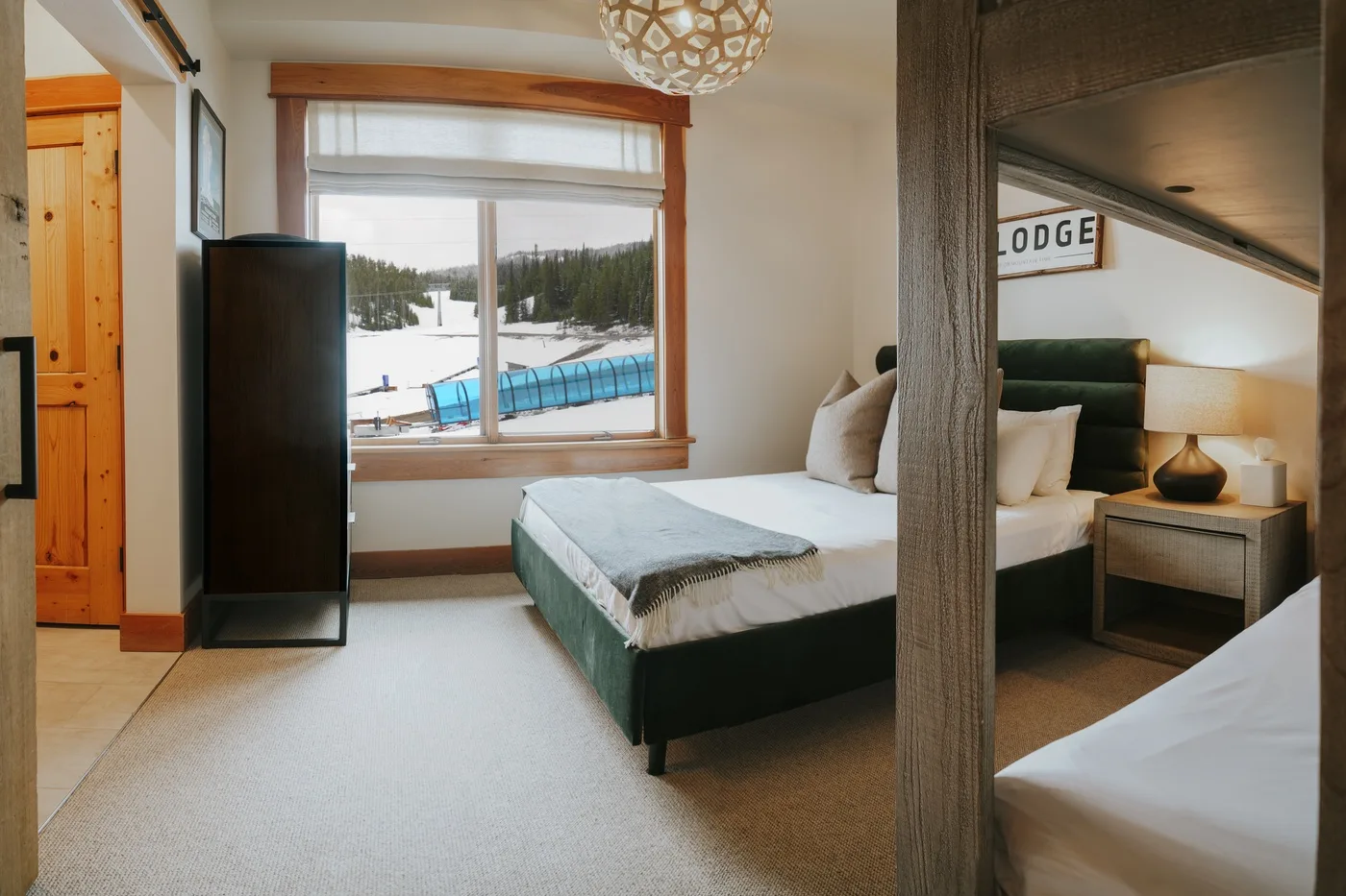Un dormitorio con una cama junto a una ventana grande que da a un paisaje nevado.