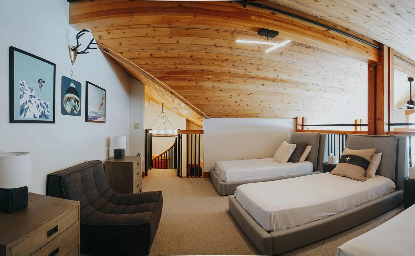 Un dormitorio con dos camas está bajo un techo de madera inclinado.