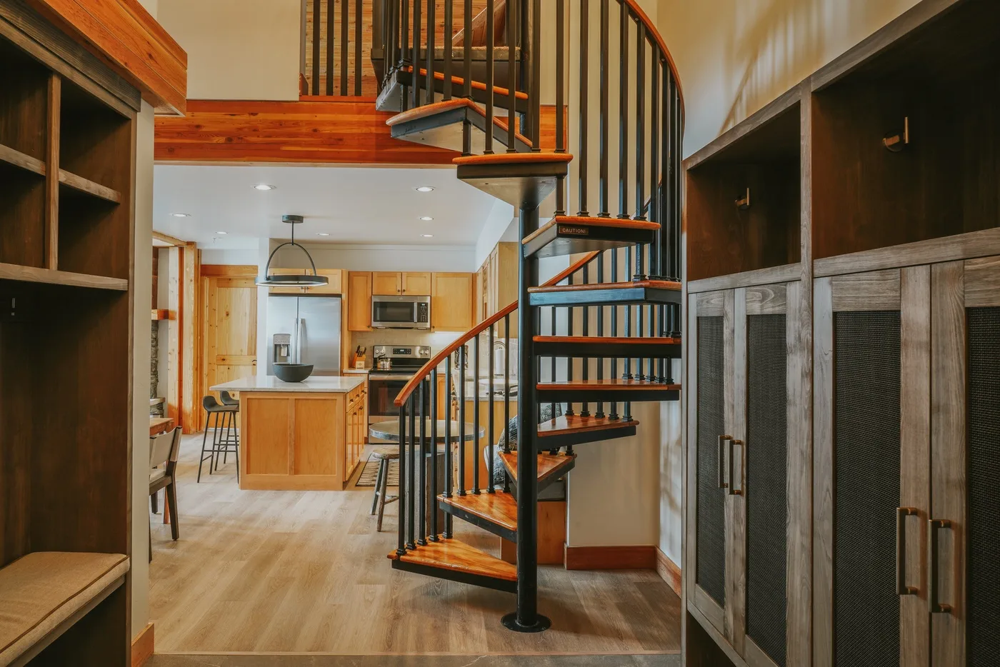 Una escalera de caracol está junto a una cocina con una isla central.