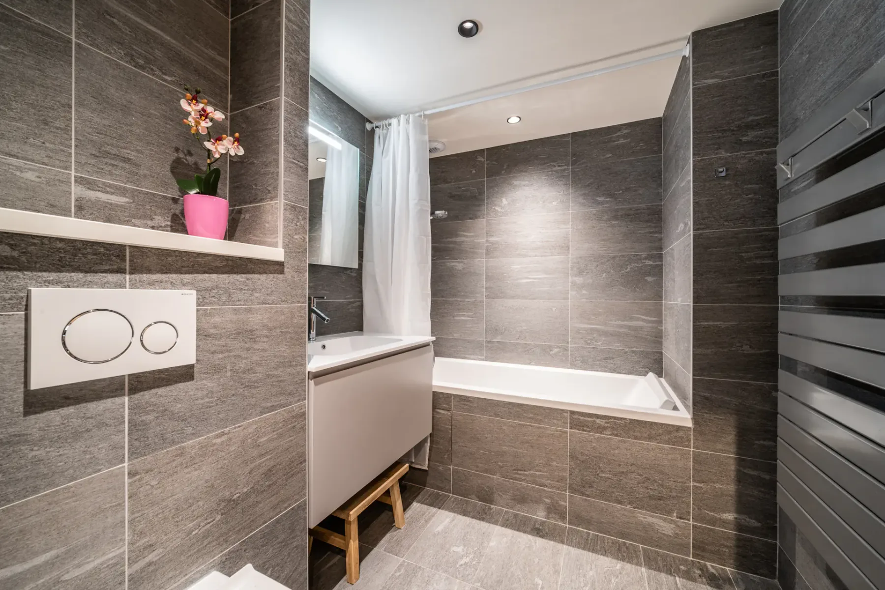 A tiled bathroom with a bathtub and a small potted flower.