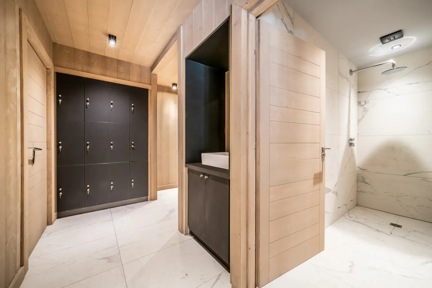 A wood-paneled entry area with dark doors and an adjacent shower.