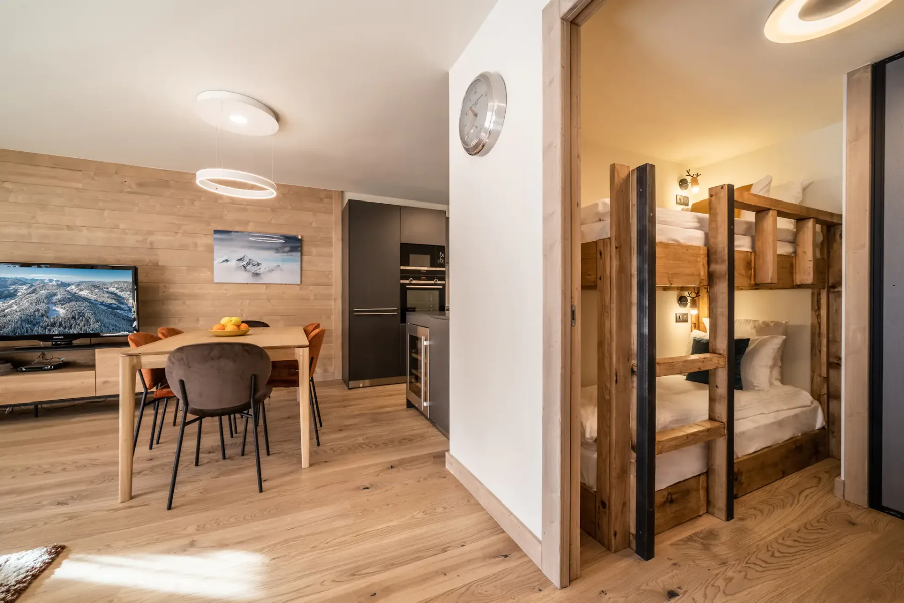 A dining and living area opens onto a bedroom with wooden bunk beds.