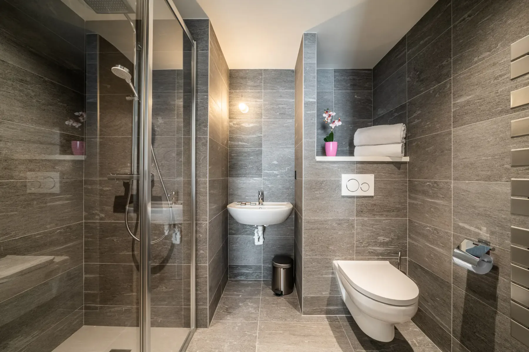 A tiled bathroom with a shower, sink, and toilet.