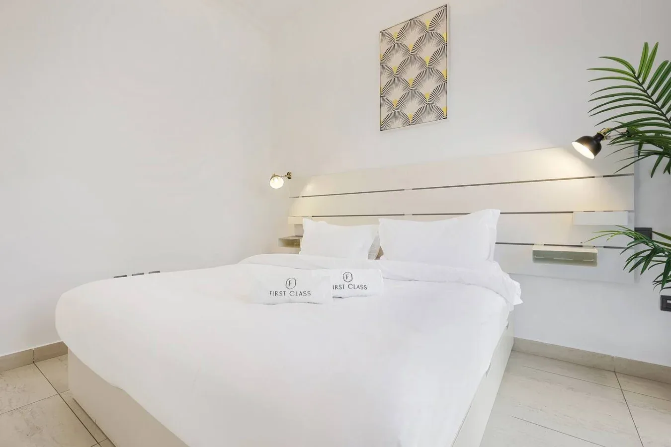 Un dormitorio luminoso cuenta con una cama bien arreglada y luces en la pared.