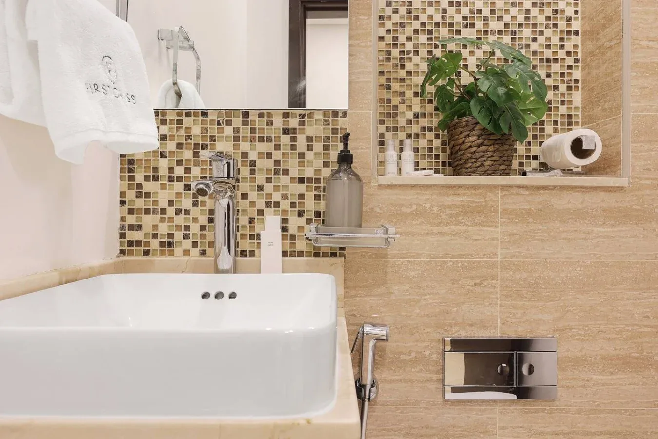 Un lavabo de baño con una pileta blanca y una pared de mosaico.