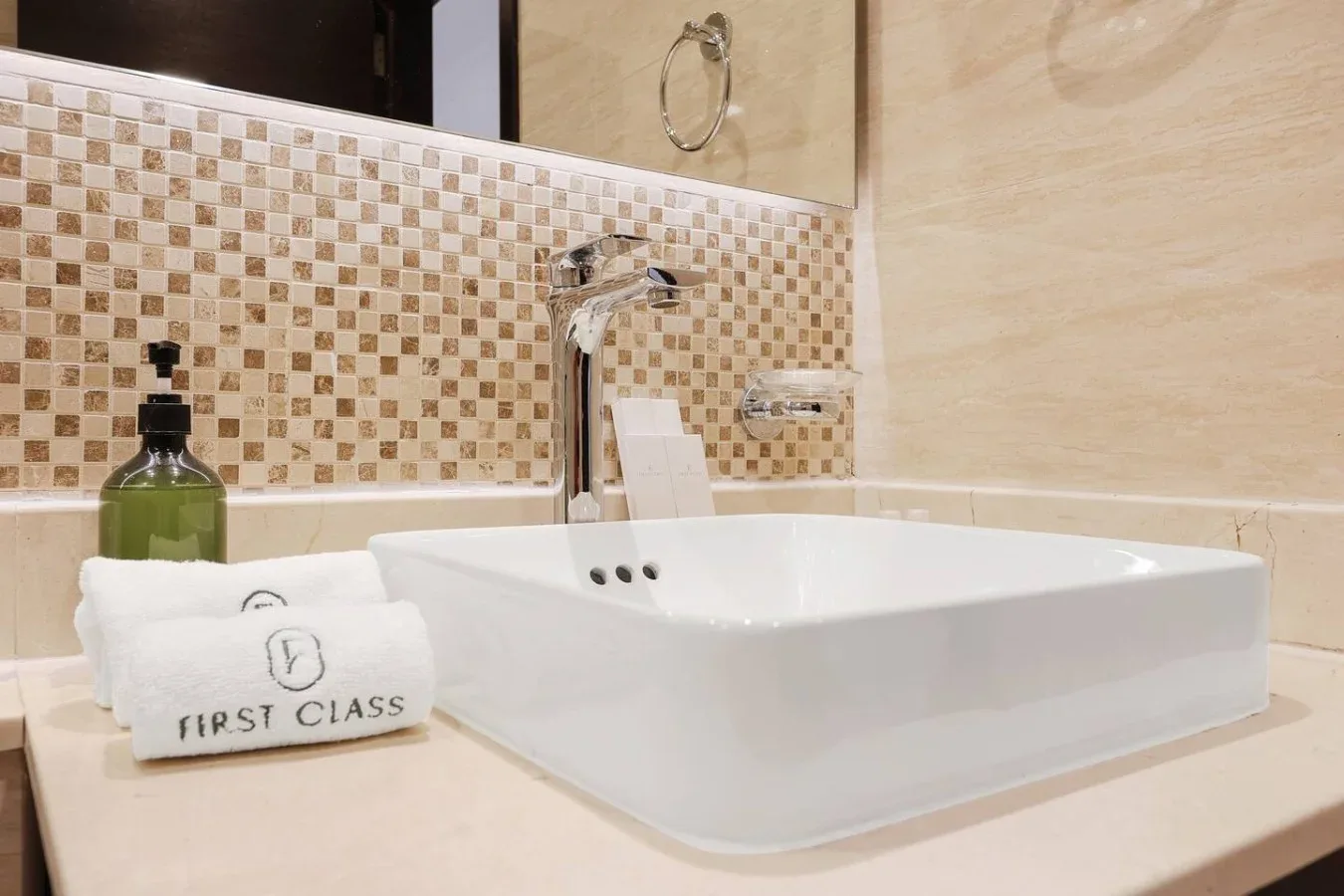 Un lavabo de baño con un lavamanos blanco sobre encimera y salpicadero de azulejos.