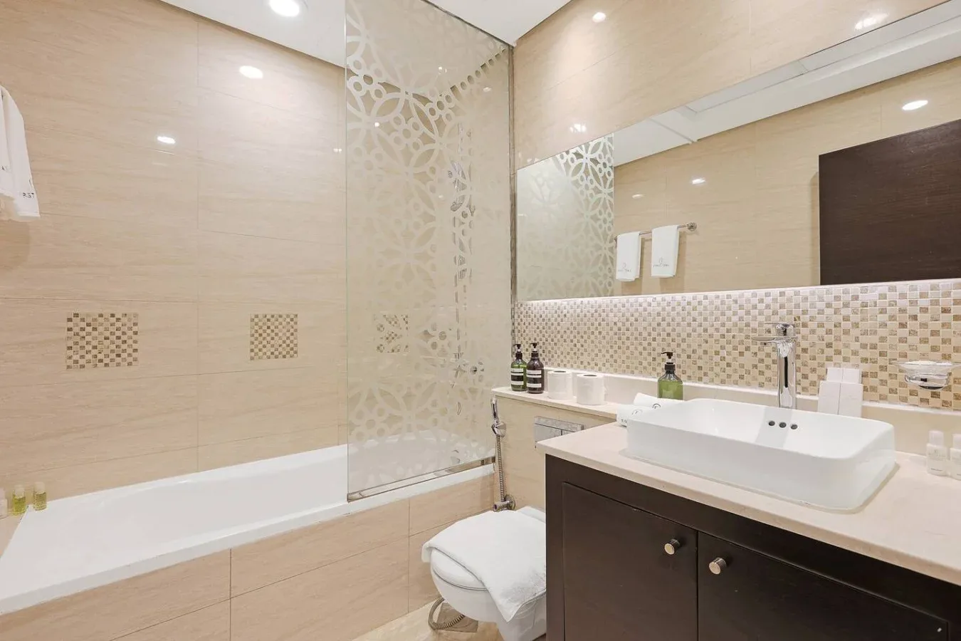 Un baño con azulejos, bañera, ducha y tocador con lavabo.