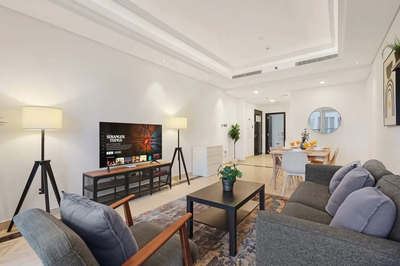 Una luminosa sala de estar y comedor con televisor, asientos y una mesa de comedor.
