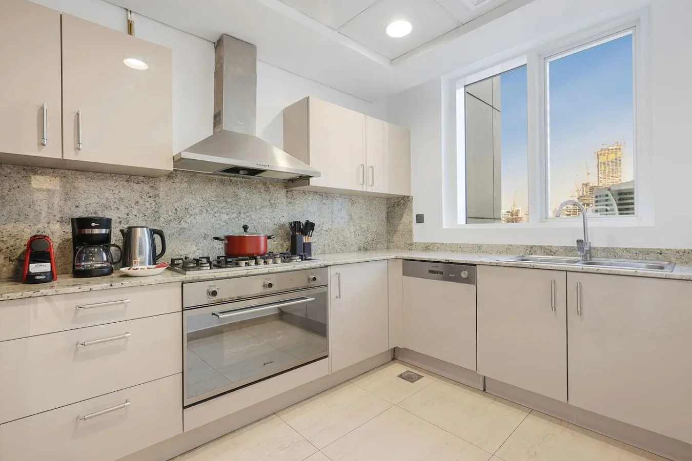 Una cocina luminosa con gabinetes claros, una estufa y una ventana amplia.