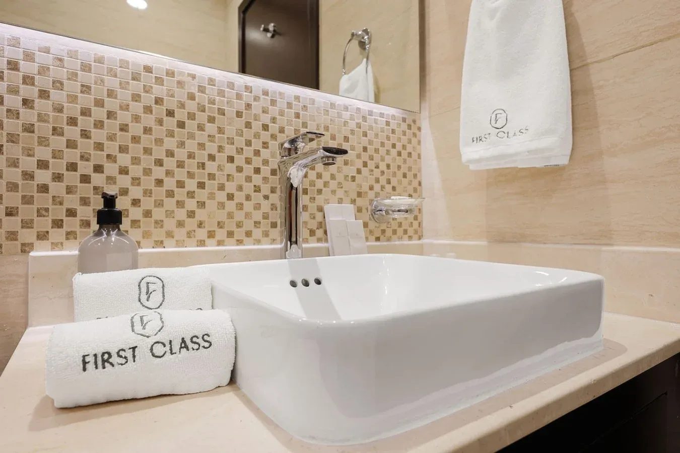 Un lavabo de baño con una pila blanca, grifo cromado y toallas dobladas.