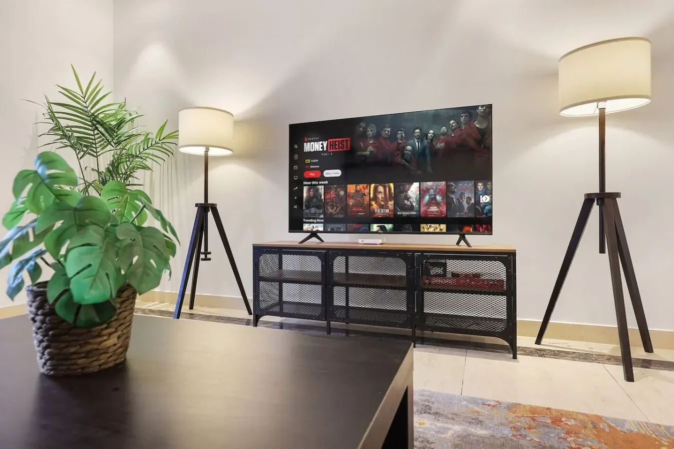 Una sala de estar con un televisor sobre un mueble y plantas a un lado.