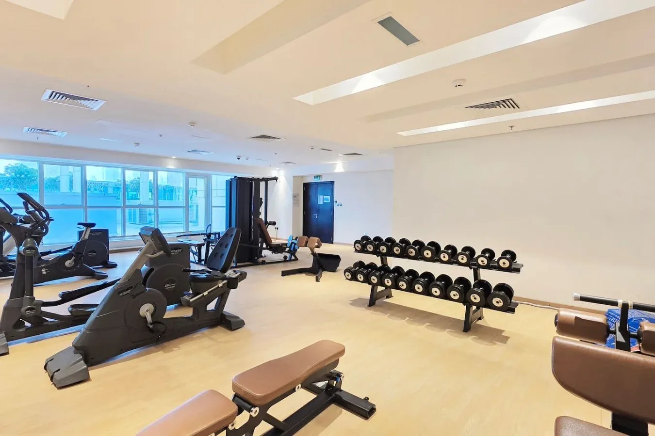 Un gimnasio con máquinas de ejercicio y filas de mancuernas.