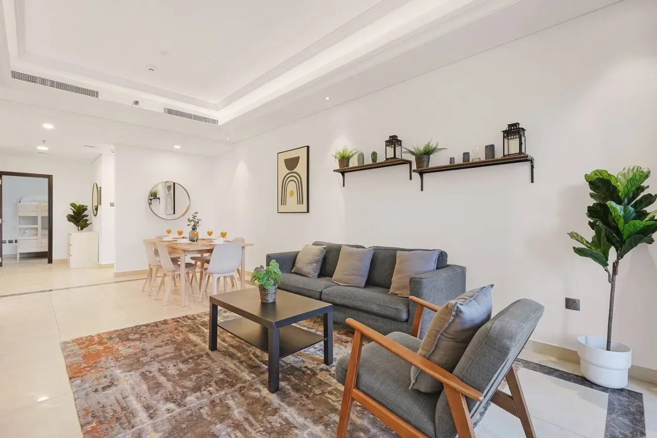 Una sala luminosa con sofá gris, sillón y zona de comedor.